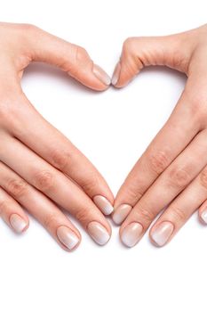 Closeup of hands of young woman forming shape of heart with her manicured fingers on white background
