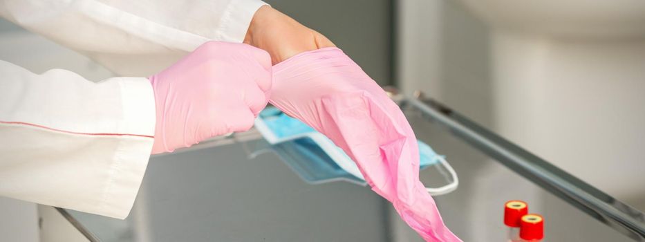 Female doctor wearing rubber protective gloves on her hands in the lab