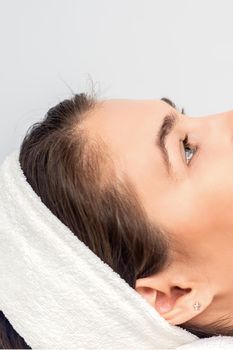 Side view portrait of pensive young woman lying and waiting for cosmetic procedure in beauty salon