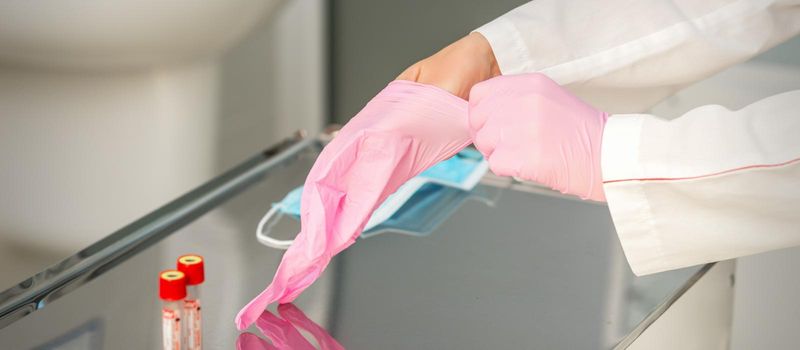 Female doctor wearing rubber protective gloves on her hands in the lab