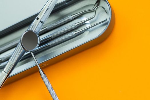 Dental mirror and other tools on orange background.