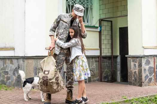 Soldier in camouflage meeting his daughter outdoors.