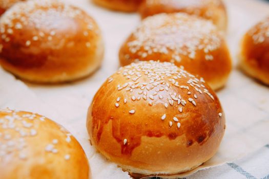 Freshly baked burger buns with sesame seeds. We cook at home.