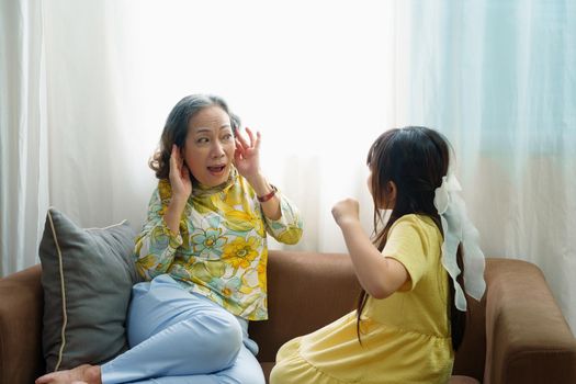 Asian portrait, granddaughter expressing displeasure by yelling at grandmother covering her ears, aggression, violence, upbringing .