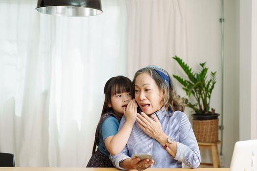 Asian portrait, grandmother and granddaughter doing leisure with little children whispering secrets between each other.