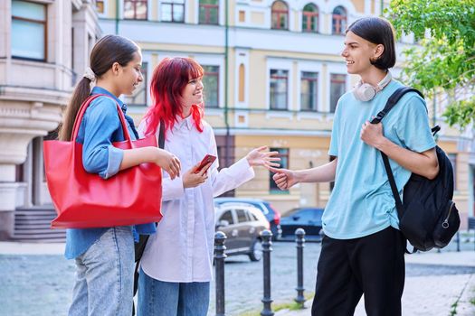 Meeting teenage friends outdoor, on street of city. Happy laughing talking young females and guy. Youth, communication, friendship, emotions, high school, college concept