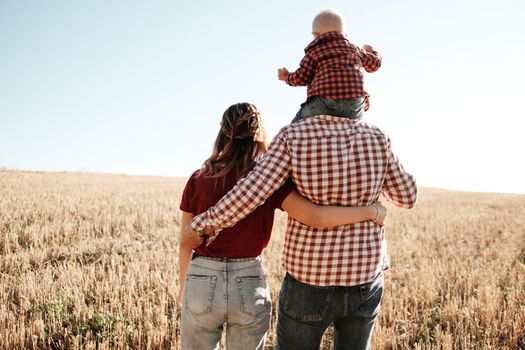 Happy Young Family Mom and Dad with Their Little Son Enjoying Summer Weekend Picnic Outside the City in Field at Sunny Day Sunset, Vacation Time Concept