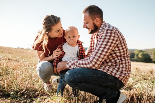 Happy Young Family Mom and Dad with Their Little Son Enjoying Summer Weekend Picnic Outside the City in Field at Sunny Day Sunset, Vacation Time Concept