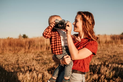 Happy Mom with Her Little Son Enjoying Summer Weekend Outside City in the Field at Sunny Day Sunset