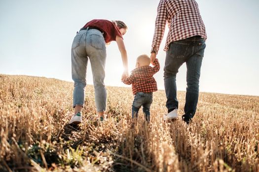 Happy Young Family Mom and Dad with Their Little Son Enjoying Summer Weekend Picnic Outside the City in Field at Sunny Day Sunset, Vacation Time Concept