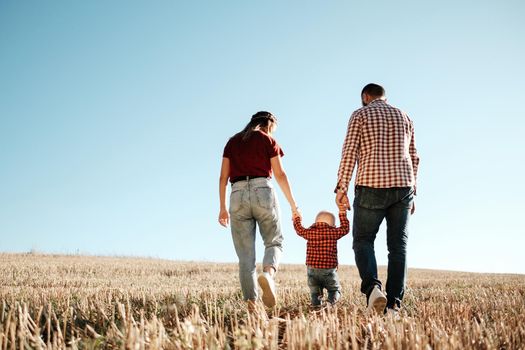 Happy Young Family Mom and Dad with Their Little Son Enjoying Summer Weekend Picnic Outside the City in Field at Sunny Day Sunset, Vacation Time Concept