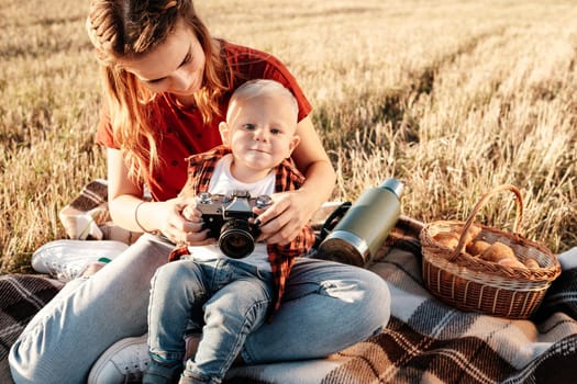 Happy Mom with Her Little Son Enjoying Summer Weekend Outside City in the Field at Sunny Day Sunset