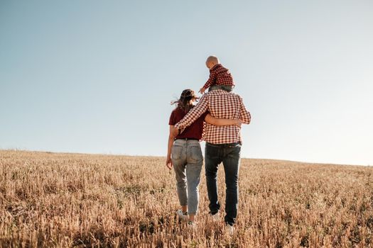 Happy Young Family Mom and Dad with Their Little Son Enjoying Summer Weekend Picnic Outside the City in Field at Sunny Day Sunset, Vacation Time Concept