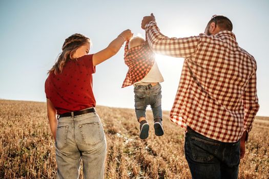 Happy Young Family Mom and Dad with Their Little Son Enjoying Summer Weekend Picnic Outside the City in Field at Sunny Day Sunset, Vacation Time Concept