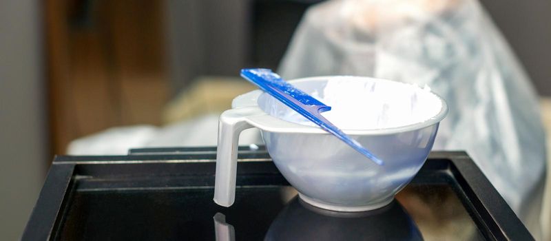 White hair dye in container on the special table in hair salon