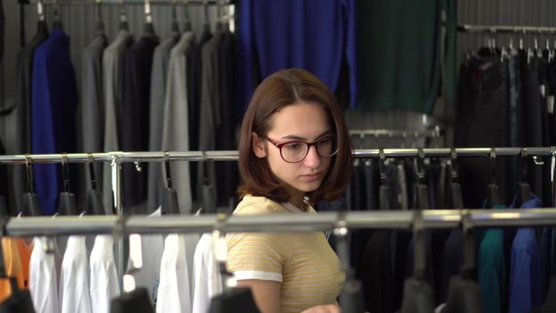 Young woman chooses clothes in the store. Clothing store. 4k