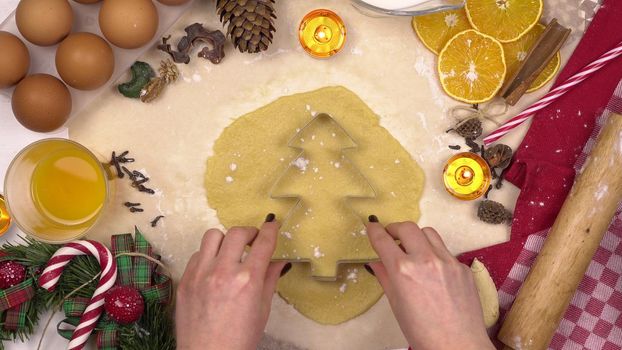 A young woman makes a traditional festive Christmas tree cookie. A figuru is placed in the dough. View from above. 4k