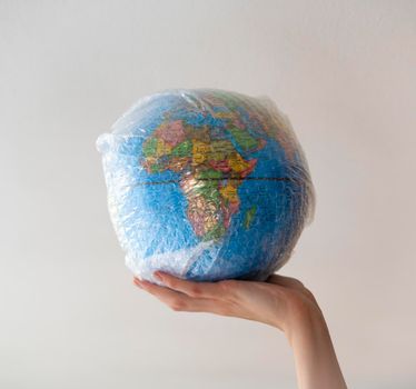 Hand holds a globe wrapped in plastic bubble wrap.