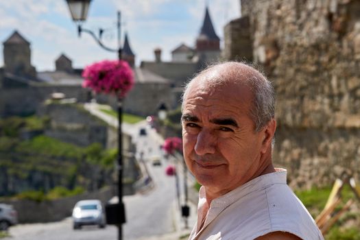 a person who is traveling or visiting a place for pleasure. An elderly man pensioner tourist goes to see the sights of an ancient fortress.