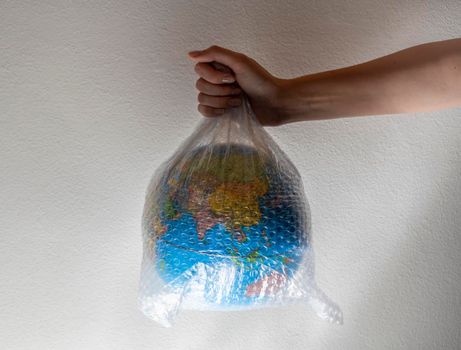 Hand holds a globe wrapped in plastic bubble wrap.