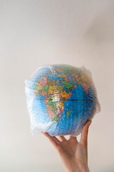 Hand holds a globe wrapped in plastic bubble wrap.