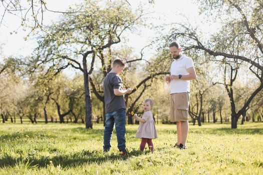 Happy family spending time together outside in nature. Father and his children playing in the garden