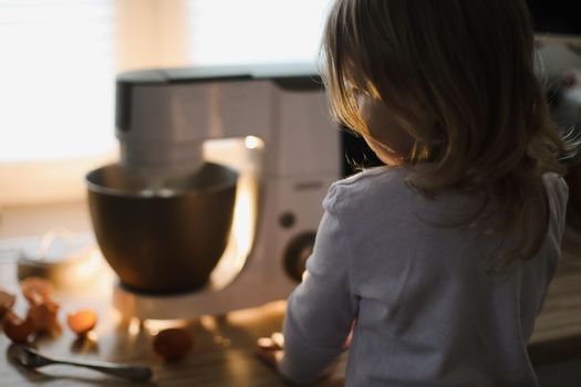 child looking at planetary mixer and baking pie in a cozy kitchen at home. High quality photo