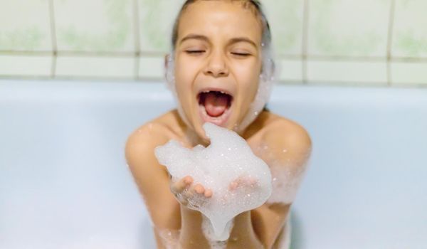 The child bathes in a bathtub soapy water. Selective focus.