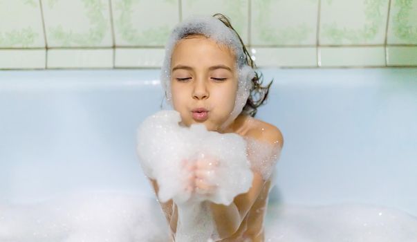 The child bathes in a bathtub soapy water. Selective focus.