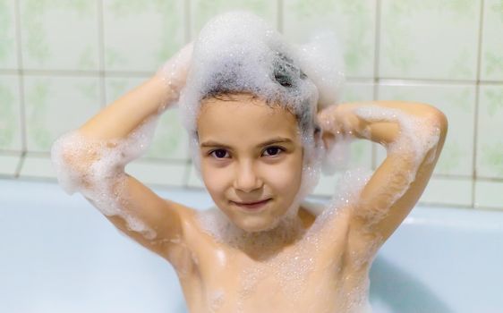 The child bathes in a bathtub soapy water. Selective focus.