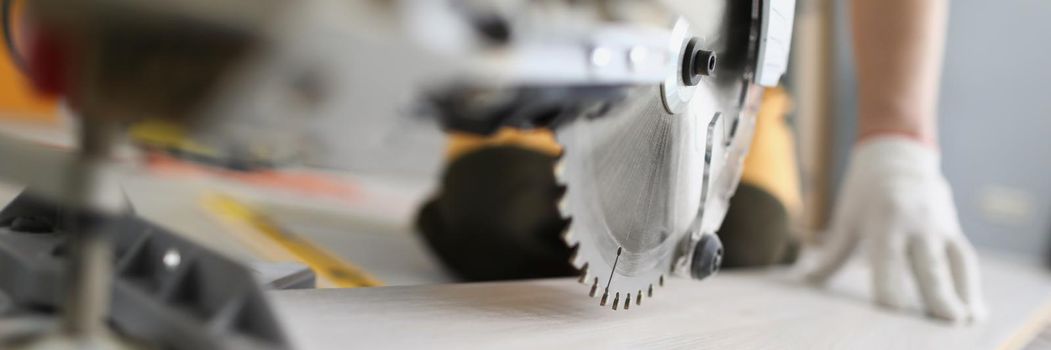 Close-up of handyman cut wooden plant with electric saw on construction site. Carpenter man work on interior change in flat. Renovation, household concept