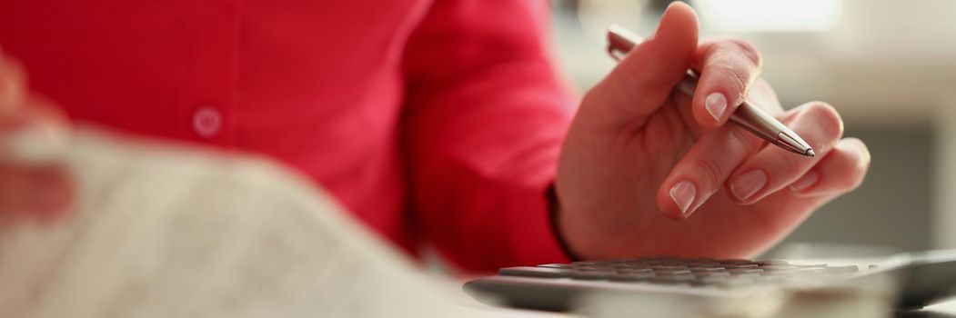 Close-up of woman calculating total amount of expense at end of month. Woman use calculator, checks and pen for notes. Bill, finance, family budget concept