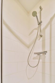 Bathtub with glass shower placed in corner near sink and mirror in small light bathroom with white tile walls