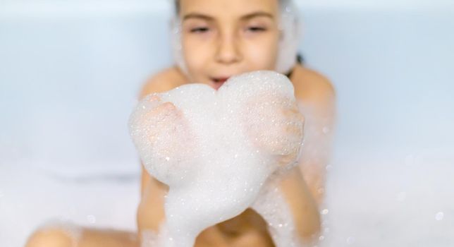 The child bathes in a bathtub soapy water. Selective focus.