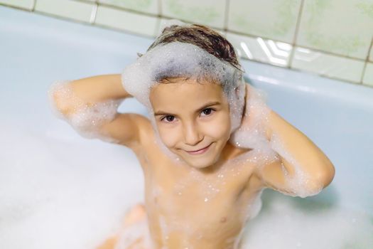 The child bathes in a bathtub soapy water. Selective focus.