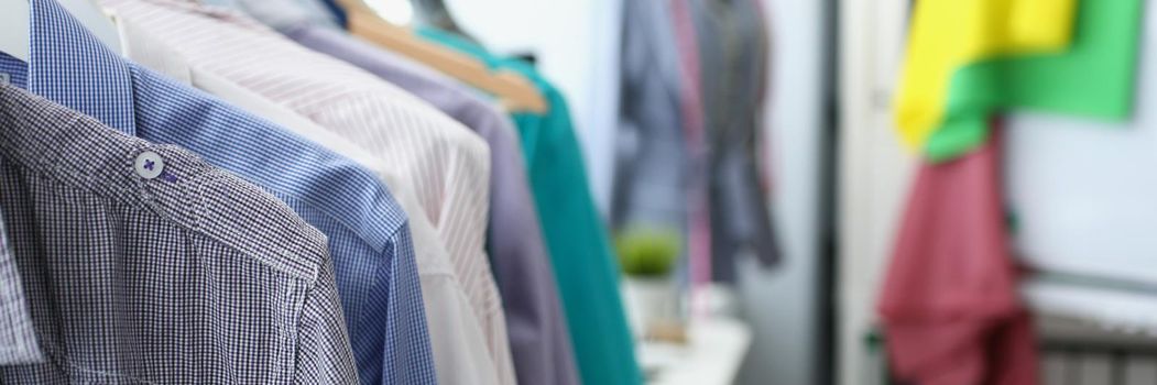 Close-up of rail with hanging of set with different colours mens shirts. Modern stylist inspirational office. Couturier showroom, atelier, fashion concept