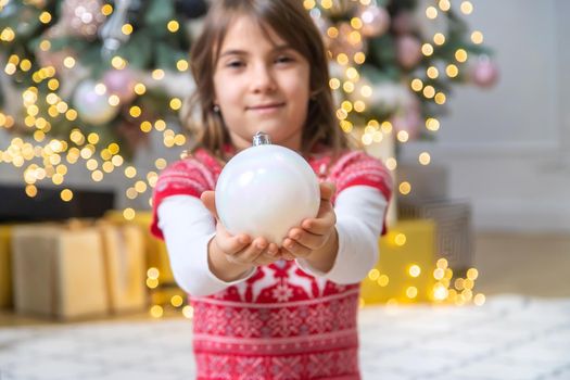 Christmas decorations on the tree in the hands of a child. Selective focus.