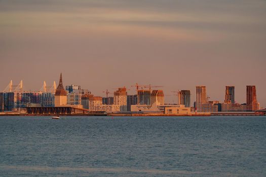 The residential complex under construction on the embankment of the Neva River on Vasilievsky island in sunset, bulk island, construction cranes. High quality photo