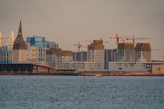 The residential complex under construction on the embankment of the Neva River on Vasilievsky island in sunset, bulk island, construction cranes. High quality photo