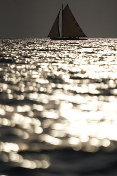 Classic sailing yacht in sea at sunset, the clear sky, sun reflection on water. High quality photo