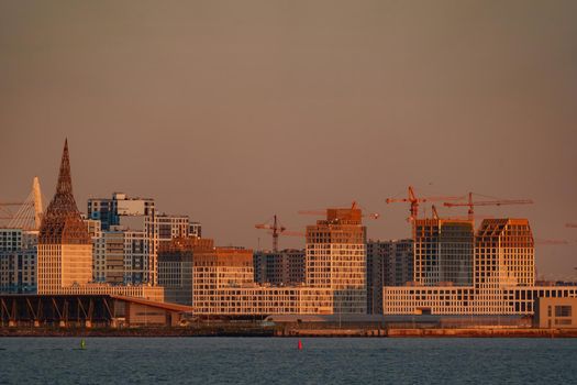 The residential complex under construction on the embankment of the Neva River on Vasilievsky island in sunset, bulk island, construction cranes. High quality photo