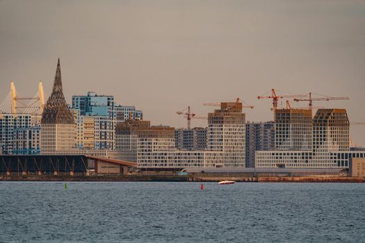 The residential complex under construction on the embankment of the Neva River on Vasilievsky island in sunset, bulk island, construction cranes. High quality photo