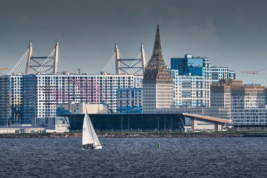 Russia, St. Petersburg, 10 June 2022: The residential complex under construction on the embankment of the Neva River on Vasilievsky island in sunny day, construction cranes, sailing yachts. High quality photo