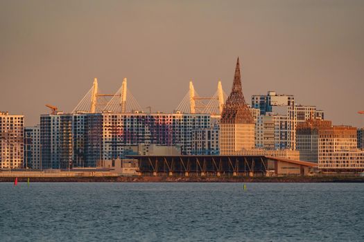 The residential complex under construction on the embankment of the Neva River on Vasilievsky island in sunset, bulk island, construction cranes. High quality photo
