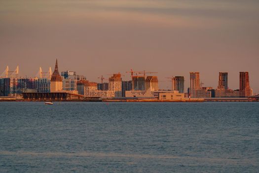 The residential complex under construction on the embankment of the Neva River on Vasilievsky island in sunset, bulk island, construction cranes. High quality photo