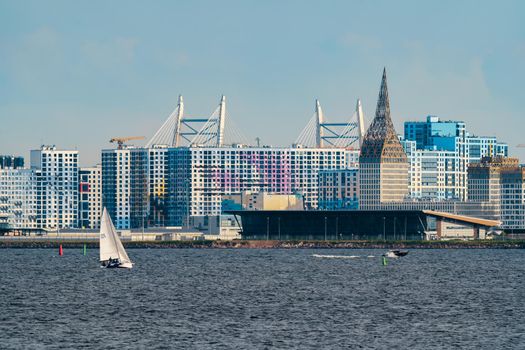 Russia, St. Petersburg, 10 June 2022: The residential complex under construction on the embankment of the Neva River on Vasilievsky island in sunny day, construction cranes, sailing yachts. High quality photo