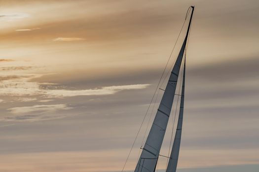 Top of mast of sailing yacht at sunset, orange sky, sail regatta, magic clouds sky. High quality photo