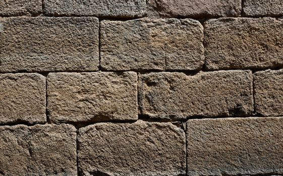 Old wall of rectangular stone bricks that are part of an old bridge