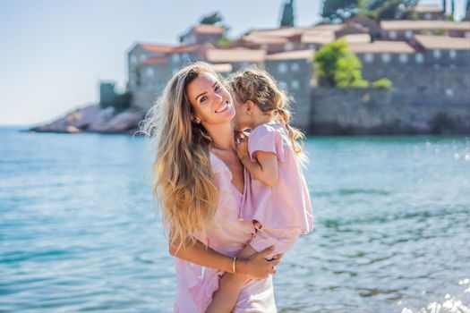 Mother and daughter tourists on background of beautiful view St. Stephen island, Sveti Stefan on the Budva Riviera, Budva, Montenegro. Travel to Montenegro concept.