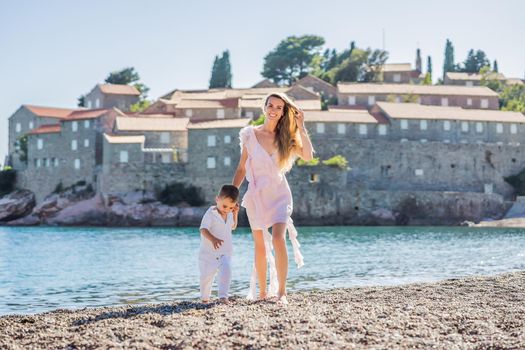 Mother and son tourists on background of beautiful view St. Stephen island, Sveti Stefan on the Budva Riviera, Budva, Montenegro. Travel to Montenegro concept.